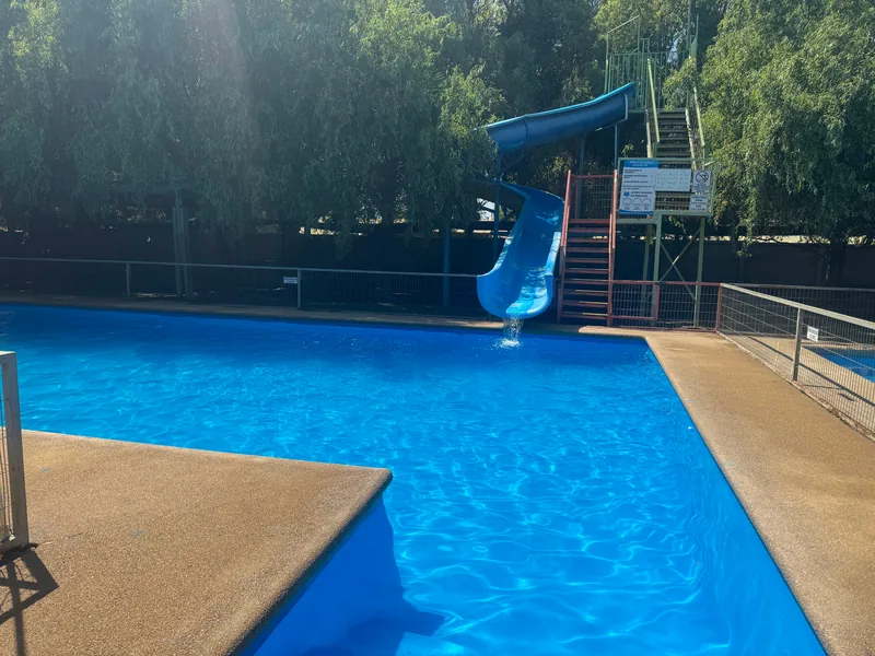 Piscina del sector 1 con tobogán azul entre los árboles